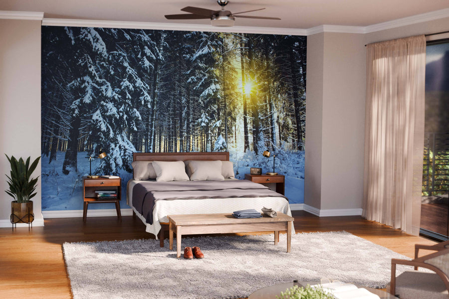 A modern open-plan living and dining space features wooden furniture, green chairs, rugs, pendant lights, and a Sunlight in the Winter Wall Mural—a peel and stick wall mural of a snowy forest—bringing a warm, nature-inspired feel.