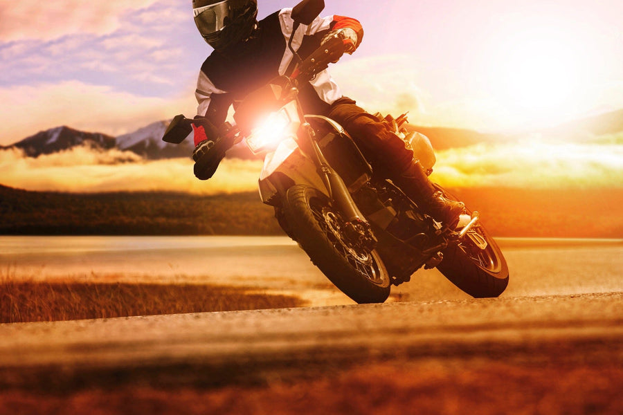 A modern garage features sleek cabinets, organized tools, and a classic motorcycle. The back wall displays the Sunset Drift Wall Mural, depicting a motorcyclist at sunset with warm sunlight creating a vibrant, dynamic atmosphere.