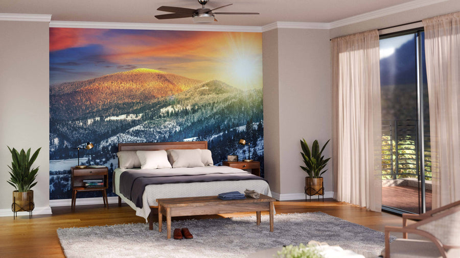 A modern open-plan living and dining room with wooden floors, stylish furniture, and the "Sunset in Winter Carpathians Wall Mural," showcasing a sunlit snowy mountain landscape that adds warmth and depth to the cozy, elegant space.