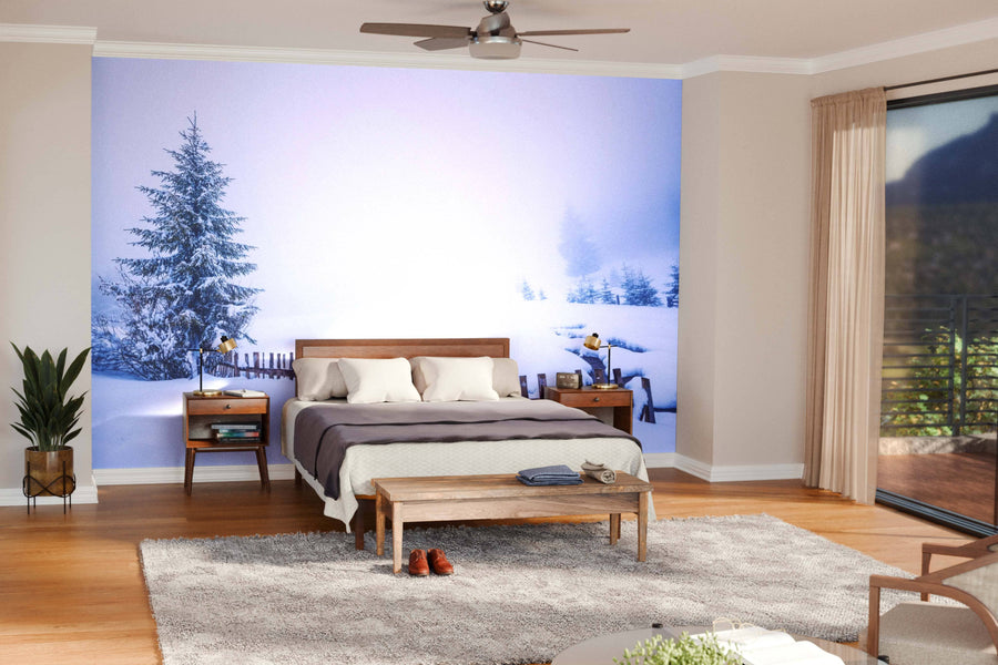 A modern living-dining room features blue armchairs, a wood coffee table, a dining set, and the Tall Slender Snowy Fir Trees Wall Mural. Wooden floors, rugs, pendant lights, and green plants complete the cozy, open space.