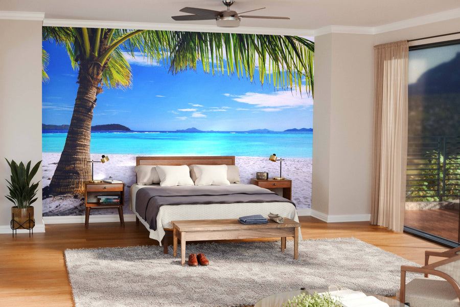 Modern living and dining room with wooden floors and furniture. The Tree on White Sand Beach Wall Mural creates an open, relaxing vibe. Pendant lights hang above the dining table; the kitchen can be seen in the background.