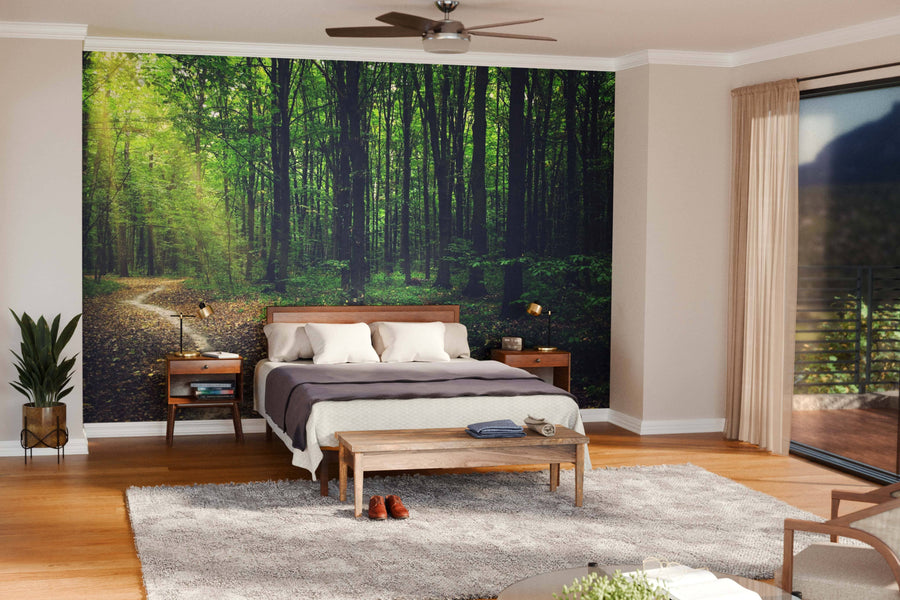 A modern open-plan living and dining room features wooden floors, stylish furniture, and a Trees in a Sunlit Green Forest Wall Mural. Pendant lights above a dark dining table create an airy, cozy, and nature-inspired atmosphere.