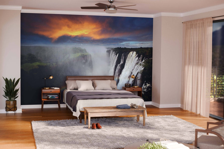 Modern open-plan living and dining area with wooden furniture and neutral walls, featuring the Victoria Falls with Rainbow Wall Mural under a fiery sunset sky as a dramatic focal point.
