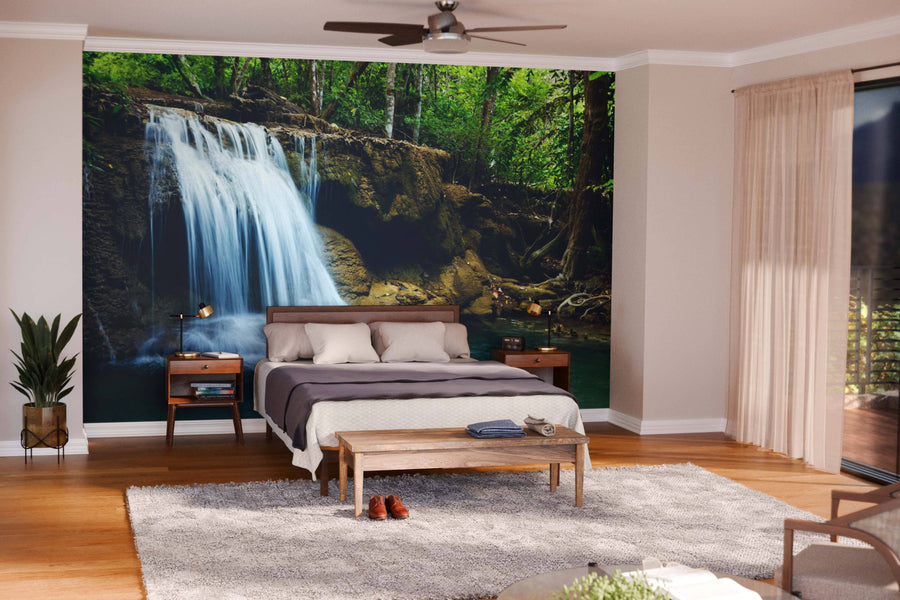 A modern living-dining room features wooden floors, stylish furniture, and the "Waterfall in a National Park Wall Mural," which divides the spaces and creates a serene, natural focal point in the contemporary open-plan interior.