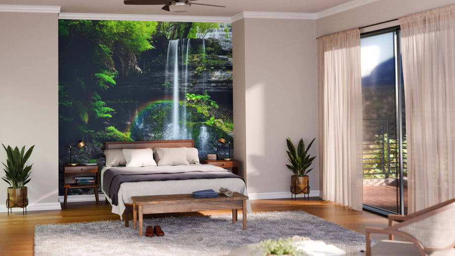 A modern open-plan living and dining room with wooden floors, blue chairs, a dining table, and a Waterfalls Wall Mural with lush greenery and a rainbow creates a stunning nature-inspired focal point in the space.