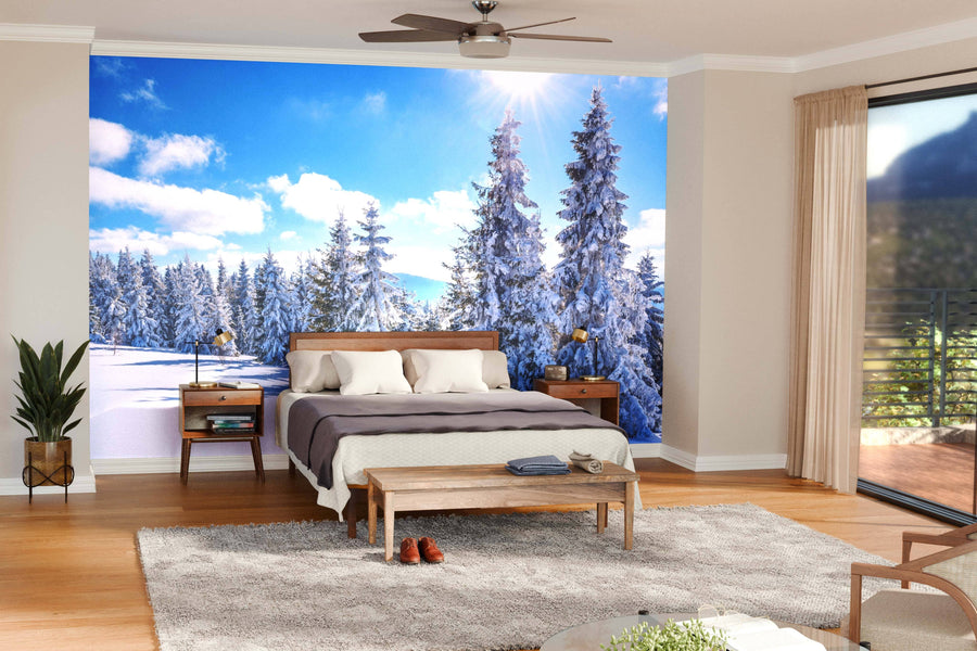 A spacious modern living-dining room features wooden floors, mid-century furniture, and a large Winter Landscape of Snowdrifts Wall Mural showcasing a snowy pine forest under a blue sky, creating a striking contrast with the warm décor.