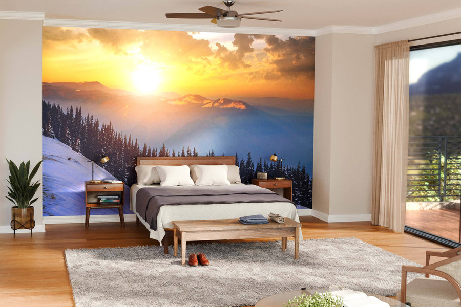 A modern open-plan living and dining room features wooden floors, teal armchairs, a large dining table, and the "Winter Landscape with High Peaks Wall Mural," casting warm light that enhances the cozy and inviting atmosphere.