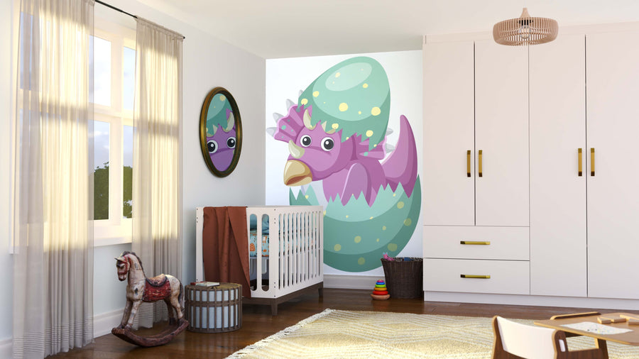A sunlit nursery with sheer curtains features a crib, toy rocking horse, and round basket. The Adorable Baby Dino Wall Mural shows a smiling purple dino hatching from a green egg, reflected in a mirror above the brown blanket.