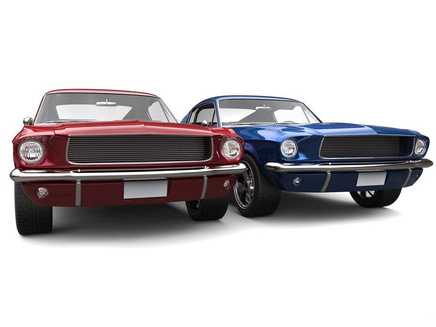 A modern bedroom with a bed, desk, and chair showcases the American Muscle Cars Wall Mural featuring two classic cars—one red and one blue—alongside wooden floors, framed car photos, and sunlight streaming through white blinds.