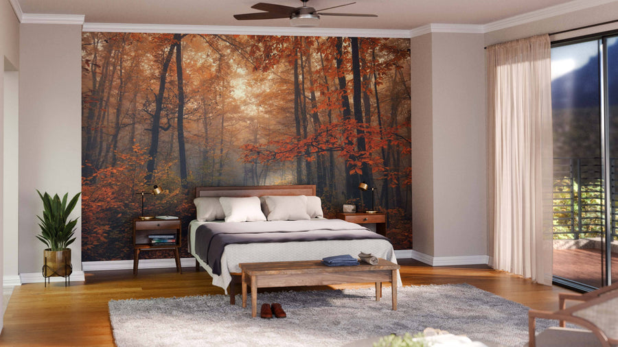 A cozy bedroom showcases the Awesome Autumn Forest Path Wall Mural behind a bed with white linens, wooden nightstands, and lamps. A plant sits on the left, while a bench, rug, and sliding glass doors with sheer curtains are on the right.