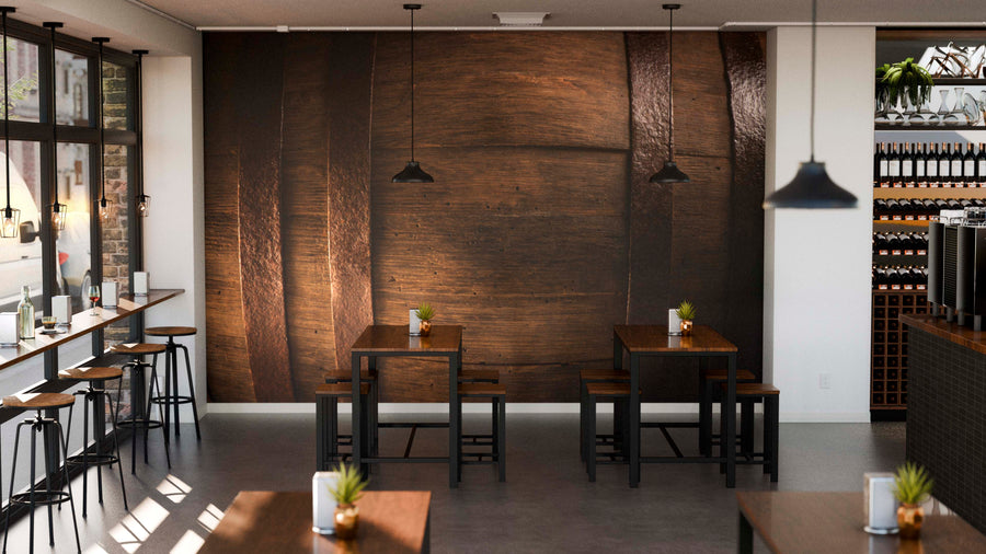 A modern cafe with wooden tables and black chairs features a stylish Barrel Wall Mural on the back wall, minimal decor, four centered tables with plants and napkin holders, and pendant lights overhead.