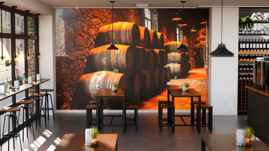 Modern cafe with wooden tables, stools, small plants, pendant lights, and the Cellar Barrel Stacks Wall Mural as a striking feature. To the right are shelves holding wine bottles and coffee machines, with sunlight streaming through large windows.
