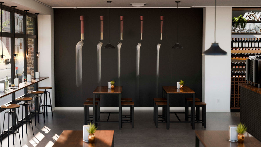 A modern café showcases wooden tables, potted plants, and a black wall adorned with the Silhouette of Wine Bottles Wall Mural. Large windows and pendant lights complete the cozy atmosphere.