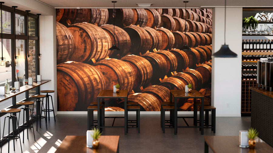 Modern bar with wooden tables, stools, plants on each table, and a Stacked Wooden Barrels Wall Mural. Pendant lights hang above. Tall windows are on the left, and wine bottle shelves line the right side.