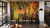 A cozy café interior with wooden tables, black stools, and pendant lights features the Vineyard in Fall Wall Mural as a focal point. Small plants decorate the tables, while large windows flood the space with natural light.