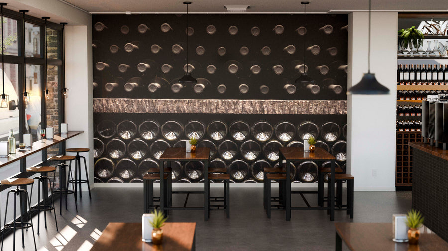A modern café with dark wood tables and plants features a decorative wall mural—Wine Bottle Rack Wall Mural. Large windows brighten the space, while shelves filled with wine bottles line the right side.
