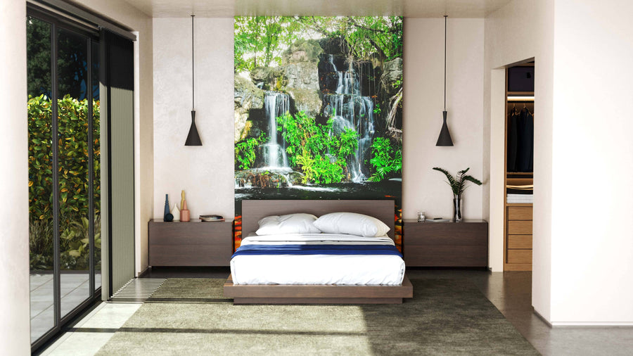 A modern bedroom with a low platform bed, bedside tables, and pendant lights. Behind the bed is the Beautiful Koi Fish Waterfall Wall Mural. Sliding glass doors open to a garden, and an open walk-in closet is visible on the right.