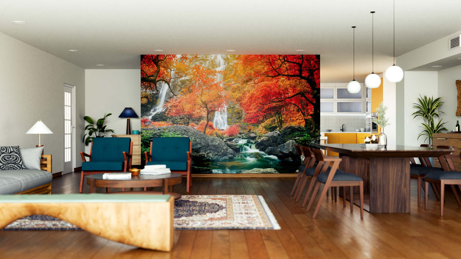A spacious, modern living-dining area with wooden floors, teal chairs, and contemporary lighting features the Beautiful Waterfalls Wall Mural—a vibrant autumn forest peel and stick mural with waterfalls and orange foliage as a striking focal point.