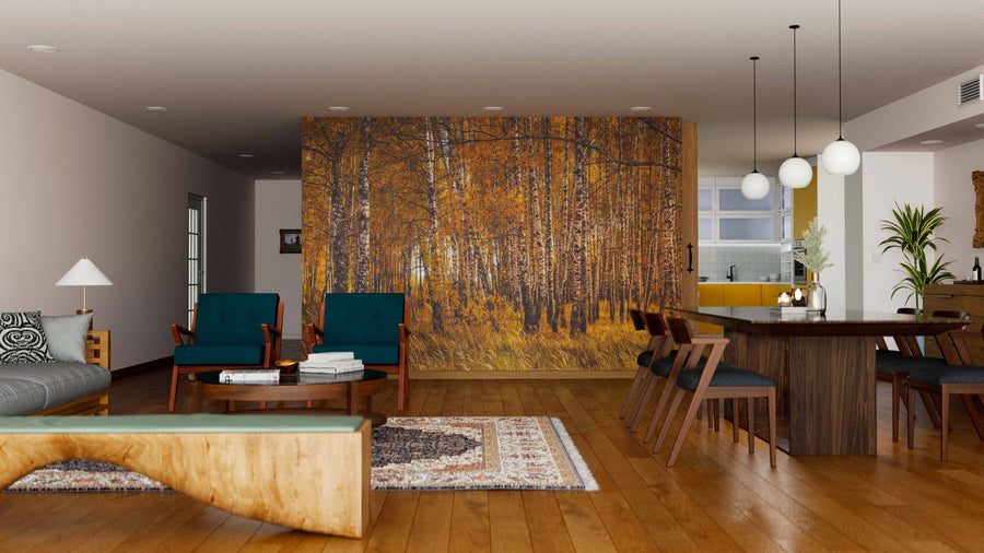 A modern living-dining area with wood flooring and earth-toned decor is divided by the Birch Trees In Autumn Wall Mural. Dark wood furniture, pendant lights, green chairs, and plants together create a cozy, elegant atmosphere.