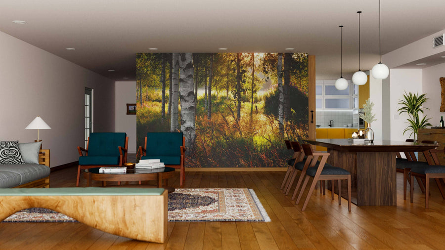 A modern open-plan living and dining room with wooden floors, teal armchairs, a Birch Trees Sun Beam Wall Mural, wooden dining table, pendant lights, open kitchen area, stylish rug, plants, and contemporary furniture.