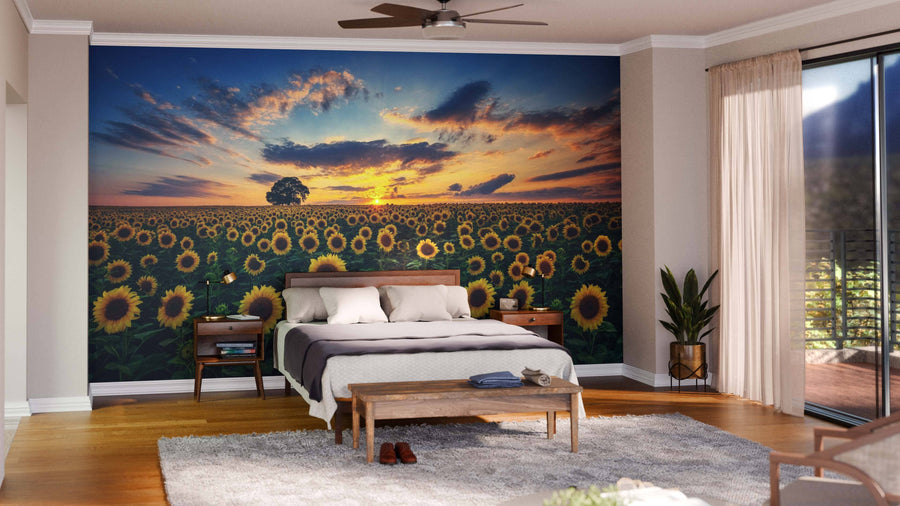 A stylish bedroom features the Blooming Sunflower Field Wall Mural behind the bed, with a wooden bed, two nightstands, a bench, gray rug, plants, hardwood floors, and floor-to-ceiling windows dressed in sheer curtains.