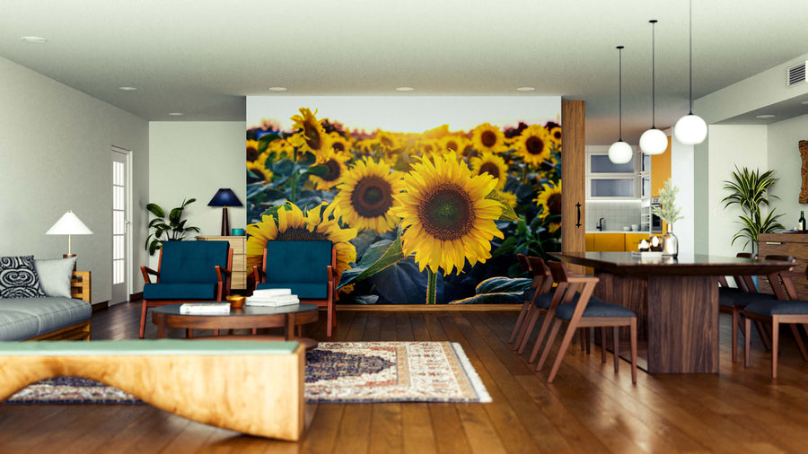 A modern living-dining room with wooden floors and blue furniture features the Blossom Beauty Wall Mural. Spherical pendant lights hang above a dark wood table, while sunlight brightens this inviting space.