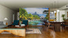 A modern living-dining room with wood floors, contemporary furniture, rugs, and pendant lights features the Bora Bora Panorama Wall Mural—a vibrant custom print of a tropical lagoon with palm trees and mountains for a relaxing, exotic vibe.