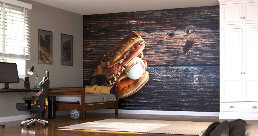 A bright bedroom features the Baseball Glove on Rustic Table Wall Mural, a bed, desk with computer, chair, two wall paintings, soccer ball on the floor, and a large white wardrobe with sunlight streaming in.
