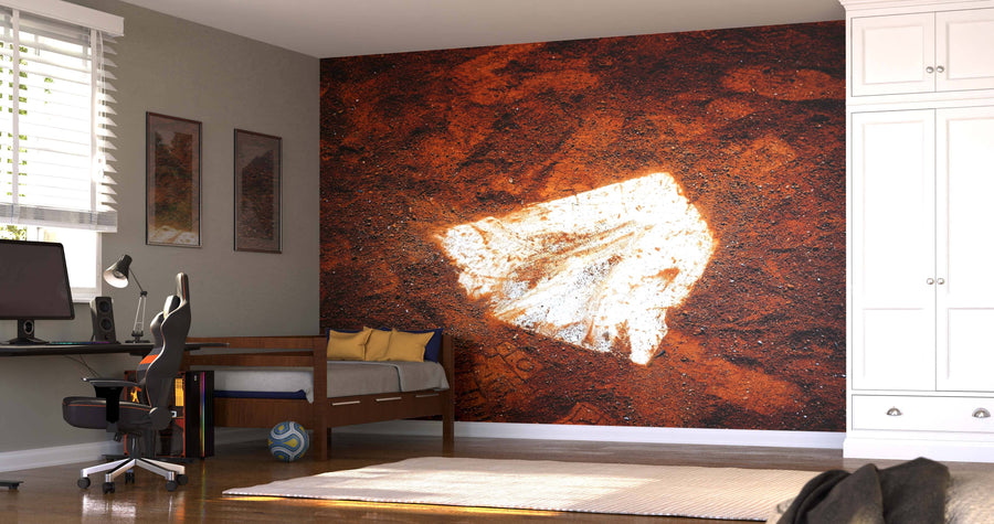A bedroom with a bed, desk, and chair features a large peel and stick wall mural of a baseball homeplate in brown dirt. Sunlight streams through blinds. Framed art hangs on the wall, a soccer ball rests on the floor, and there’s a white wardrobe.