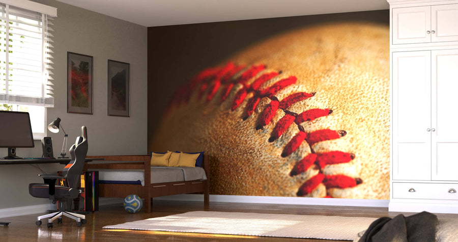 A modern bedroom with a desk, bed, and white wardrobe features the Baseball Stitches Wall Mural. Sunlight streams through blinds, illuminating a soccer ball on the floor near plush pillows.