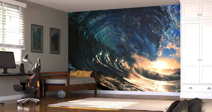 A modern bedroom showcases the Big Kahuna Wall Mural, depicting a crashing ocean wave with sunlight. The space includes a desk with a computer, wooden daybed with yellow pillows, a wardrobe, and a soccer ball on the wooden floor.