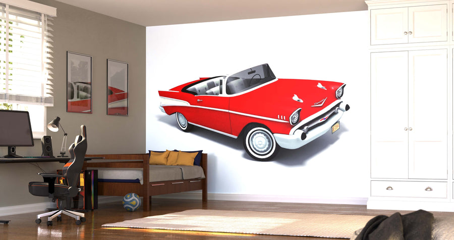 A modern bedroom with a workspace and single bed features the Classic Car Wall Mural, depicting a classic red convertible. The room includes light walls, wood floors, a computer desk, shelves, a soccer ball, and a white wardrobe.