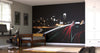 A modern bedroom with a desk, chair, twin bed, window with blinds, white wardrobe, and a soccer ball on the floor. The wall displays the Downtown Skyline and Passing Cars Wall Mural showing a city skyline at night with car light trails.