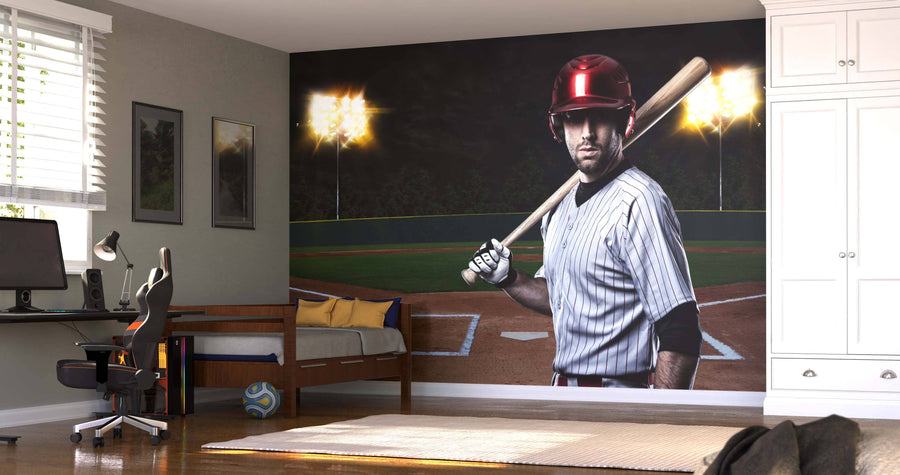 A bedroom includes a workspace, bed, and the Game Time Wall Mural depicting a serious baseball player in a red helmet and striped uniform on a lit night field. Neutral walls, modern furniture, and sports decor complete the look.