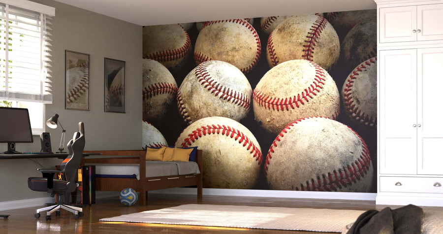 A bedroom showcases the Old Baseballs Wall Mural, paired with a bed topped with blue and yellow pillows, a computer desk, modern chair, striped rug, white wardrobe, and sunlight streaming through the blinds.