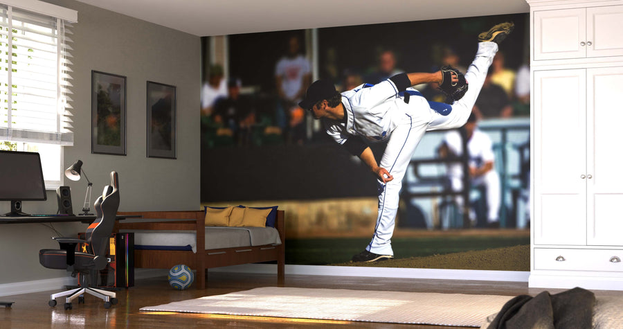 A modern bedroom features a desk, chair, daybed, and the Pitch in Motion Wall Mural of a baseball player pitching. Sunlight filters through white blinds onto the tidy, sports-themed space where a soccer ball sits on the wooden floor.