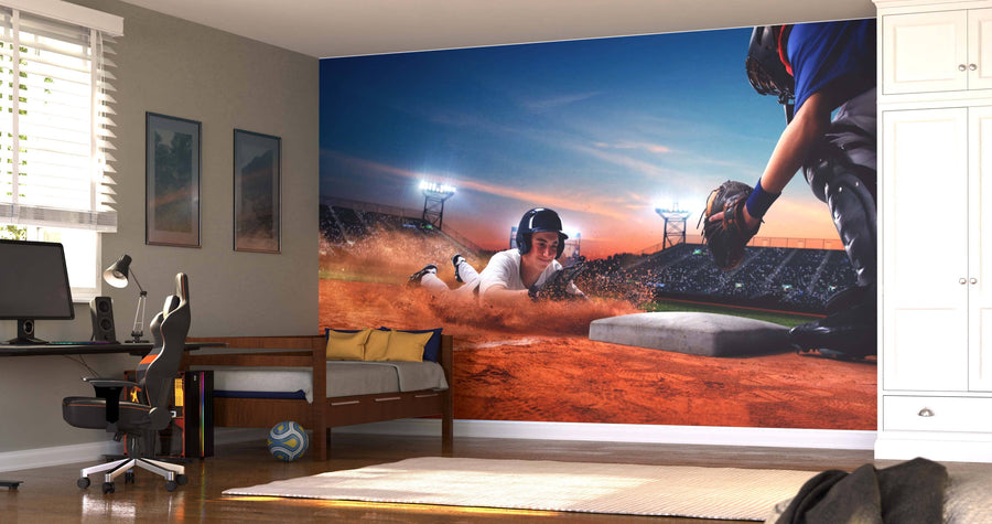 A bedroom features the Players Infield Wall Mural—a peel and stick design of a baseball player sliding home as a catcher tags him. Paired with a daybed, desk, chair, white cabinets, and sunlit wooden floors, it adds vibrant energy to the space.