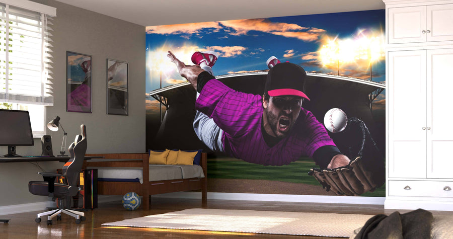 A bedroom showcases a Professional Baseball Player Wall Mural, depicting a player diving for a catch. The room also contains a desk with computer, chair, bed, soccer ball, wardrobe, and is lit by daylight through white-blinded windows.