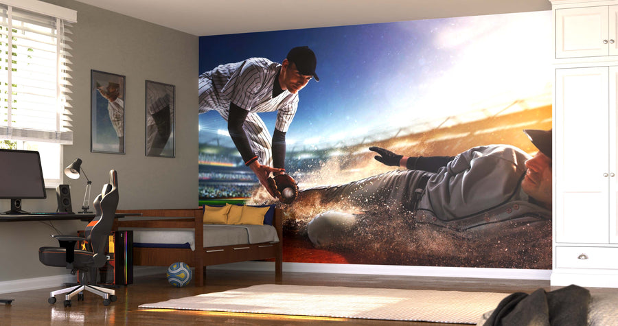 A bedroom showcases the Sliding Into Victory Wall Mural depicting a dramatic baseball scene. The space also features a desk, chair, bed, framed art, and sunlight shining through blinds onto a wooden floor.