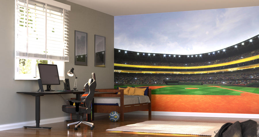 A modern bedroom features the Under the Stadium Lights Wall Mural, a single bed with blue and yellow bedding, a black gaming chair at a computer desk, framed pictures, white blinds, and a soccer ball on the floor.