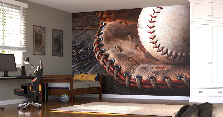A modern bedroom centers around the Used Baseball Equipment Wall Mural, showing a baseball in an old glove. The space also has a desk with computer, bed, white cabinets, wall art, a soccer ball on the floor, and sunlight streaming through blinds.