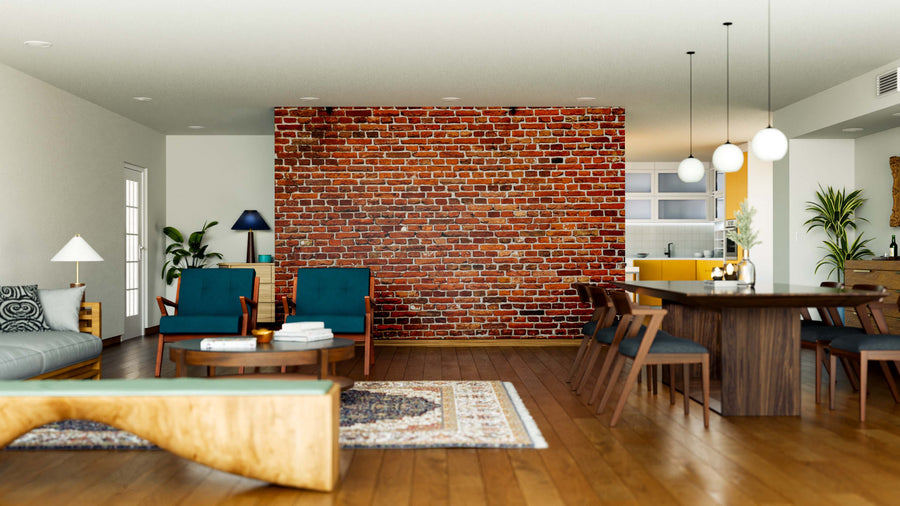 A modern open living and dining space features a Brick Wall Wall Mural, teal armchairs, a wooden coffee table, rug, gray sofa, pendant lights above the dining table, plants as decor, and a visible kitchen in the background.