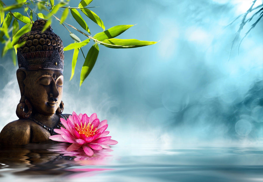 A modern open-plan living and dining room with wood floors, teal chairs, a large table, and the “Buddha in Meditation Wall Mural” featuring a serene Buddha, bamboo, and lotus on a misty blue background. Contemporary lights hang above.