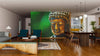 A modern living and dining space with wood floors, mid-century furniture, and a large Buddha with Green Background Wall Mural. Pendant lights accent the dining table, while a rug adds comfort near the seating area.