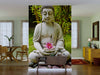 A serene living room showcases the "Buddha with Lotus and Bamboo Leaves Wall Mural," featuring a stone Buddha statue, pink lotus, and bamboo. Modern wooden furniture and green walls complete the peaceful, zen-inspired space.