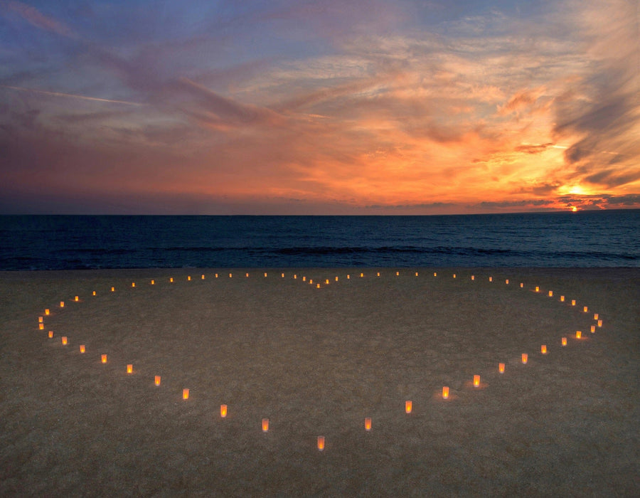 A modern living and dining area with wood floors and furniture features the Candles Heart Wall Mural, showcasing a sunset ocean scene with heart-shaped candles, bringing warmth and romance to the contemporary space.