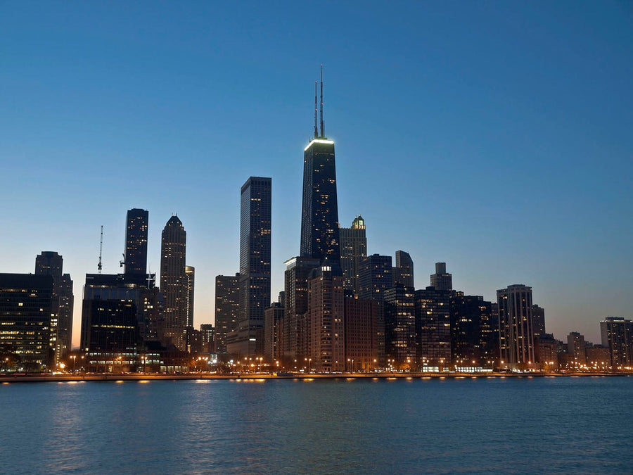 A modern conference room with a long wooden table, black chairs, and a large window wall featuring the Chicago Hancock at Night Wall Mural. Glass walls show another office area; the floor is light wood with a dark blue rug.