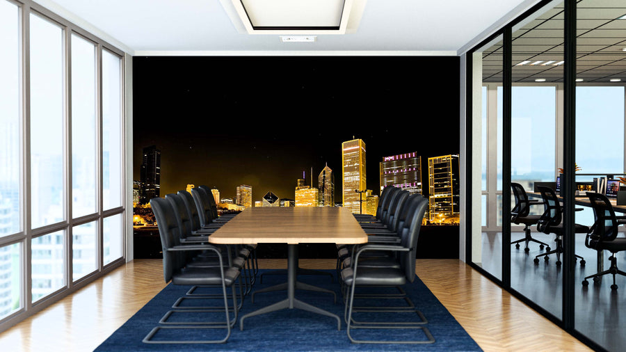 A modern conference room with a long table and black chairs on a blue rug features the Chicago Night Photography Wall Mural, showcasing the city skyline at night. Glass walls offer views of bright natural light from large windows.