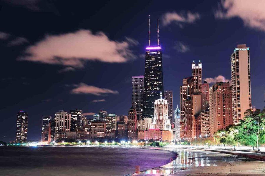 A modern conference room with a long wooden table, black chairs, and glass walls features the Chicago Lakefront Hancock Night Wall Mural, displaying illuminated skyscrapers and clouds for a vibrant urban atmosphere.