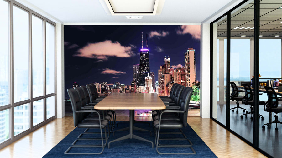A modern conference room with a long wooden table, black chairs, and glass walls features the Chicago Lakefront Hancock Night Wall Mural, displaying illuminated skyscrapers and clouds for a vibrant urban atmosphere.